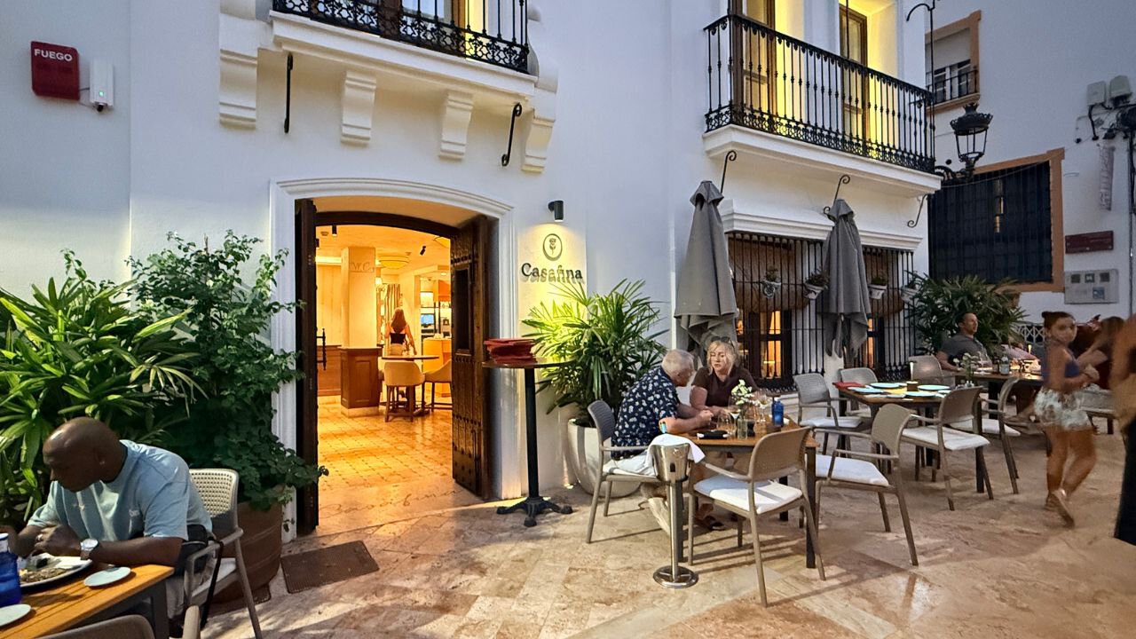Casa Fina restaurant in Estepona, with a warmly lit entrance and diners at outdoor tables beneath iron balconies.